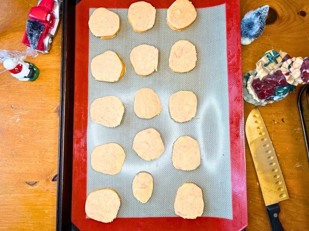 A lined baking sheet with orange and cardamom slices of dough.