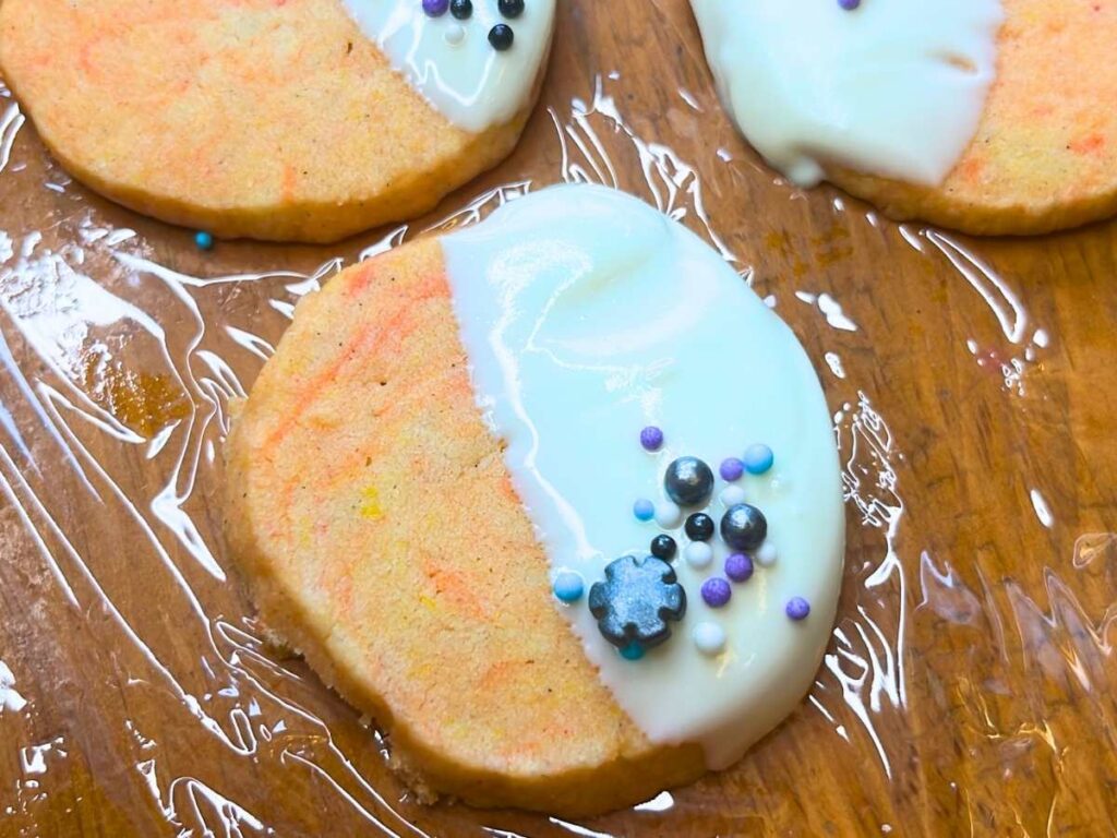 Orange and cardamom cookies decorated with white chocloate and sprinkles