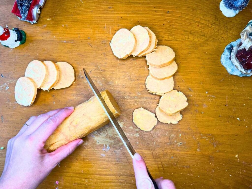 A woman cutting orange and cardamom shortbread dough into cookies.