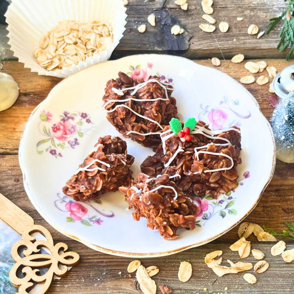 A pink floral plate with some chocolate haystack cookies. There are oats sprinkled on the table.