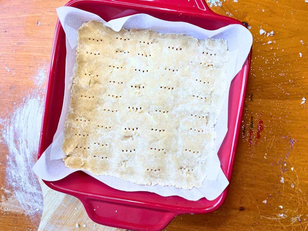 Shortbread cookie dough in a red casserole dish.