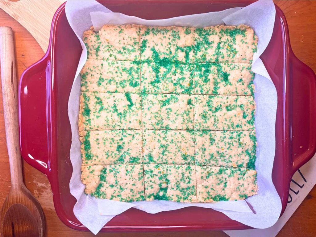 Shortbread cookies sprinkled with green sanding sugar. The cookies are sliced into rectangles.