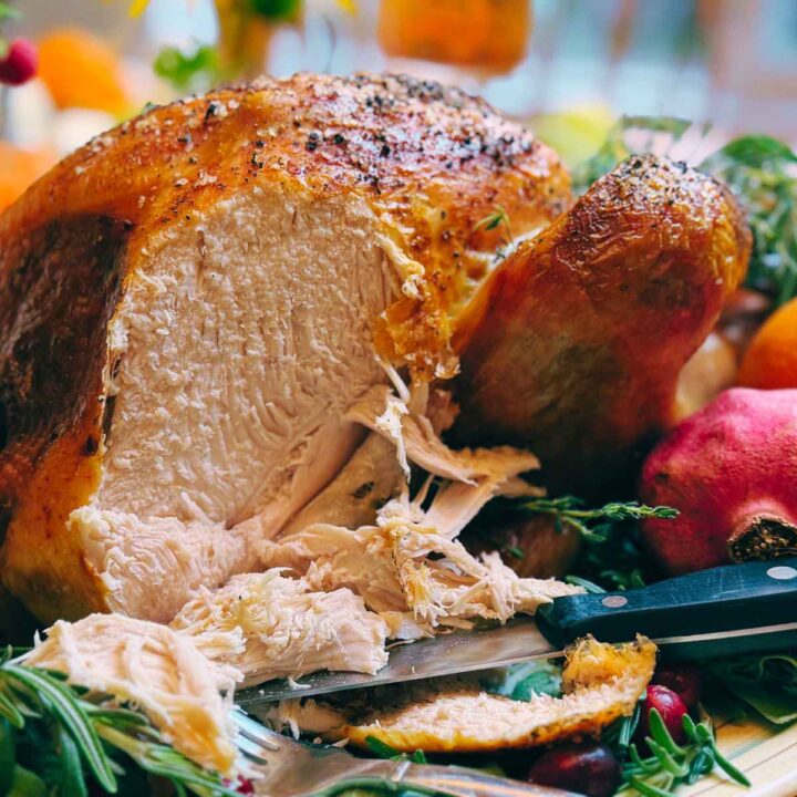 A sliced turkey on a platter with fresh herbs.