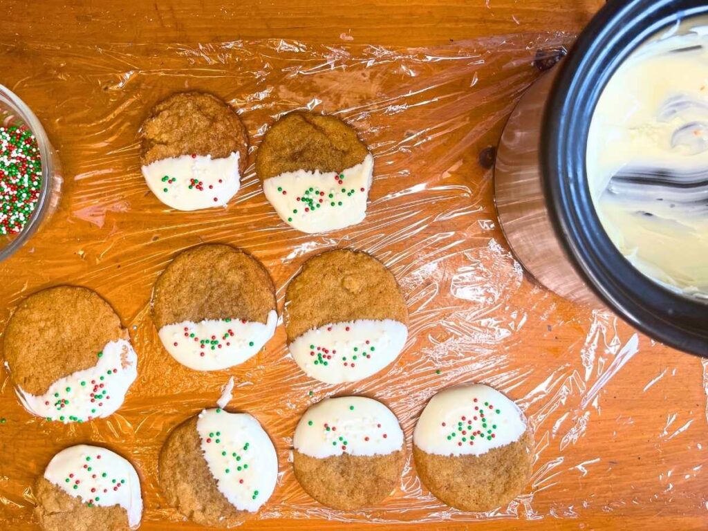 Gingerbread cookies that have been decorated on a sheet of plastic wrap.