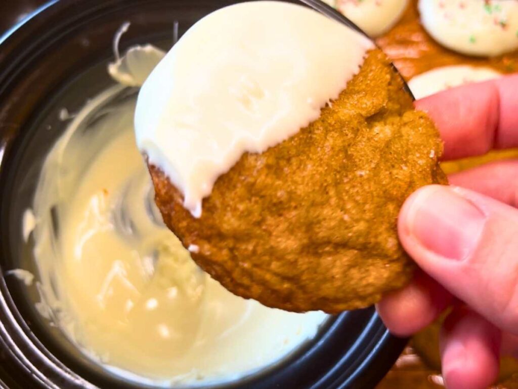 A woman has dipped a gingerbread cookie in white chocolate.