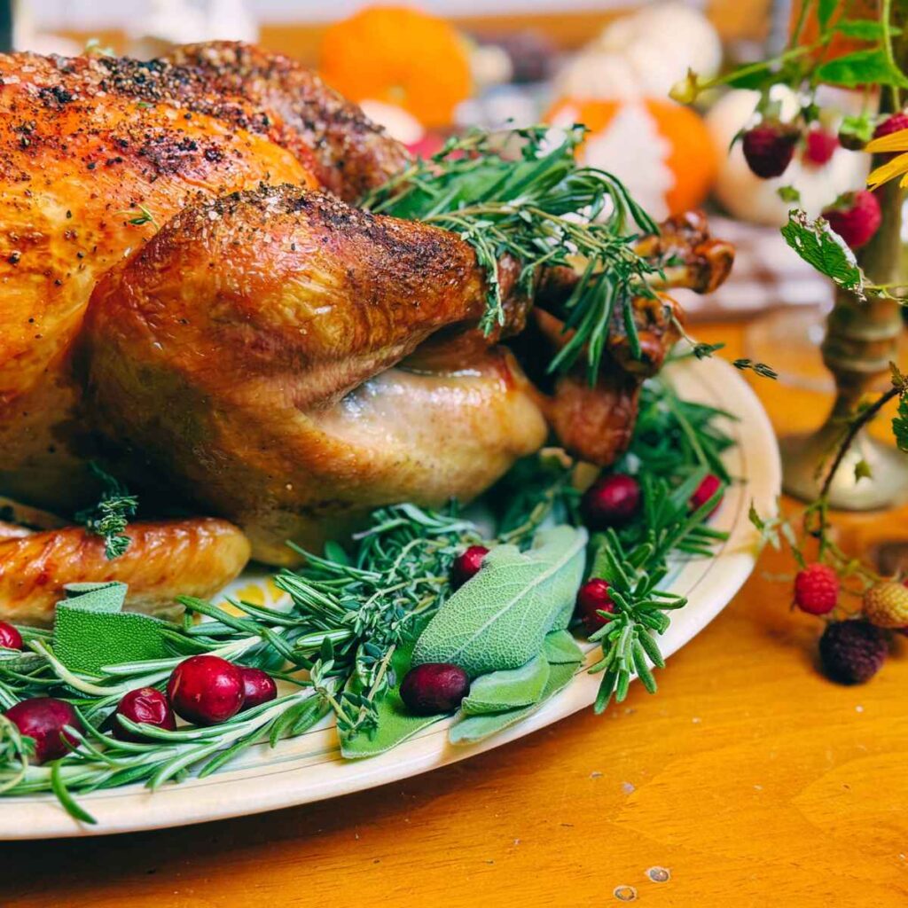 A roast turkey on a platter decorated with fresh herbs.