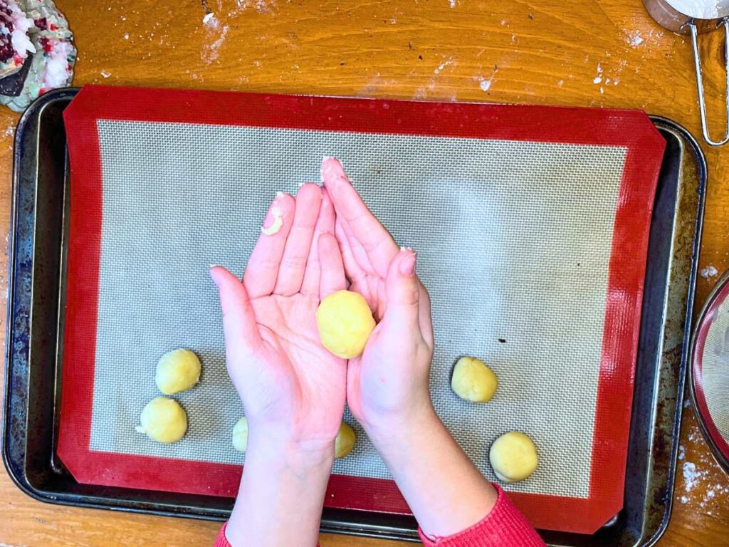 A child is holding a rolled ball of dough.