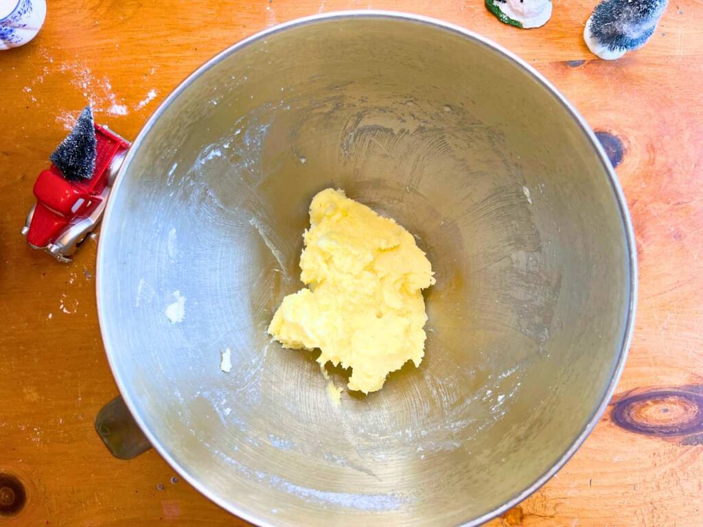 A metal bowl with creamed butter and sugar in the bottom.