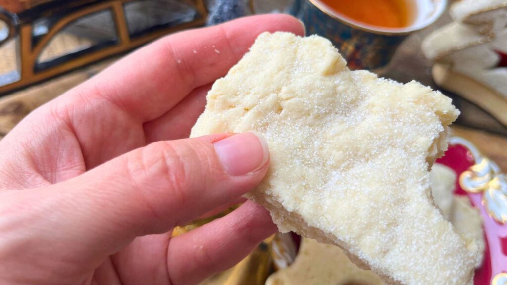 A woman is holding a shortbread cookie.