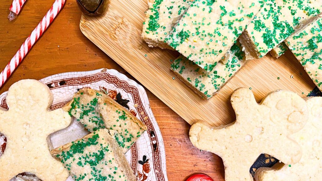 Some shortbread cookies on a brown floral plate. There are more on a wooden serving board.