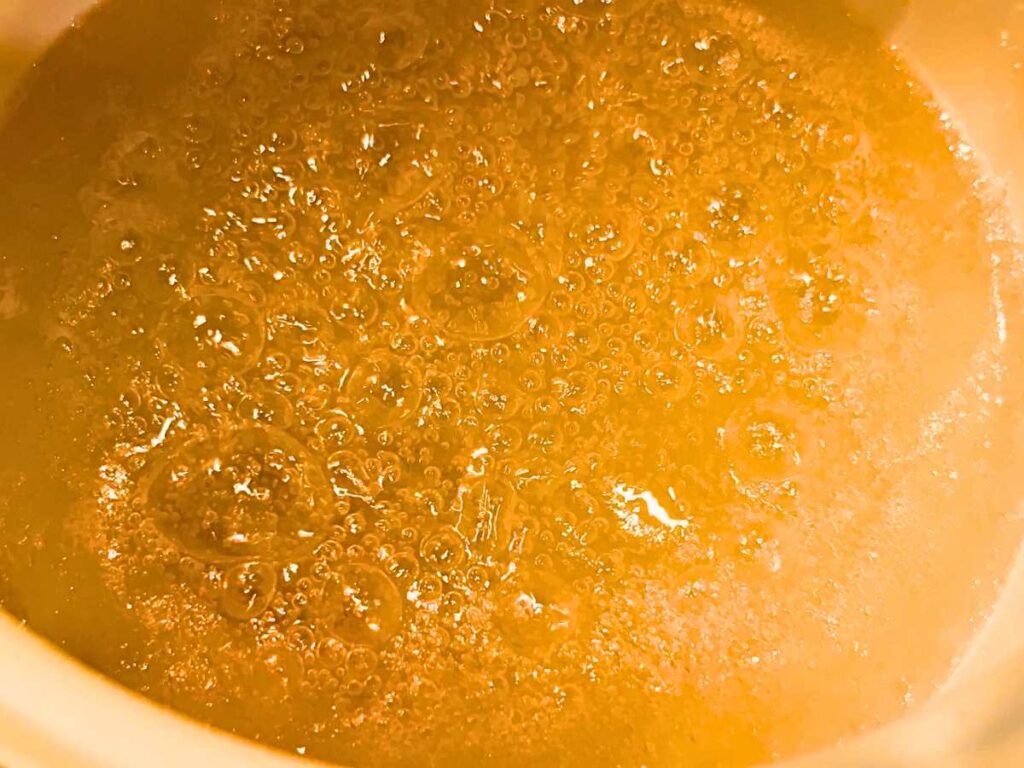 Caramel boiling in a white sauce pot.