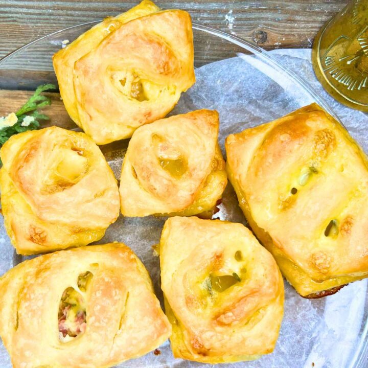 Puff pastry appetizers on a glass plate. They are stuffed with Brie, honey, and rosemary.