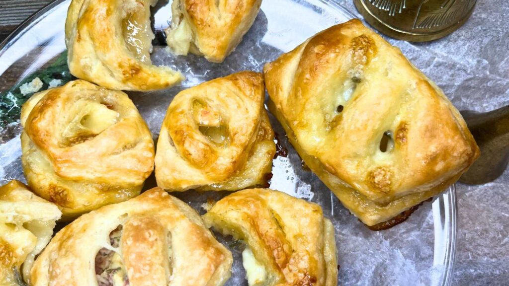 A glass plate with puff pastry appetizers filled with Brie and Honey.