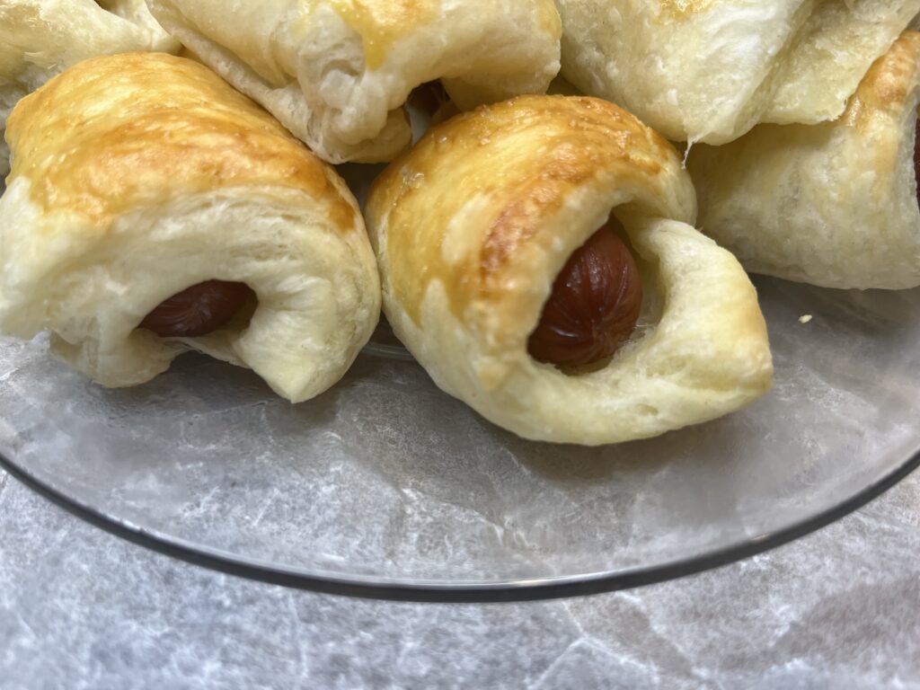 A plate of baked pigs in a blanket appetizers.