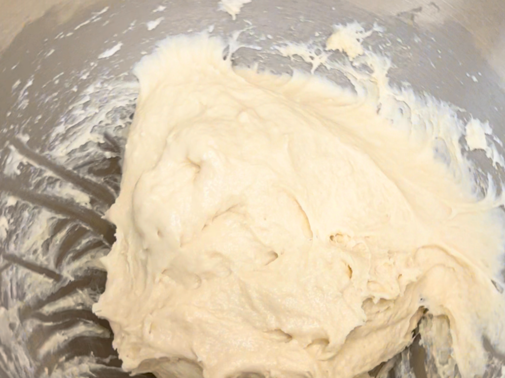 A ball of pastry dough in the bowl of a stand mixer.
