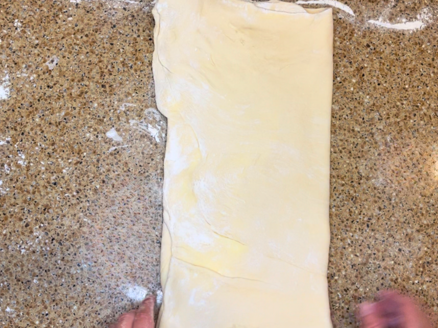 Woman folding the final third of the pastry dough.