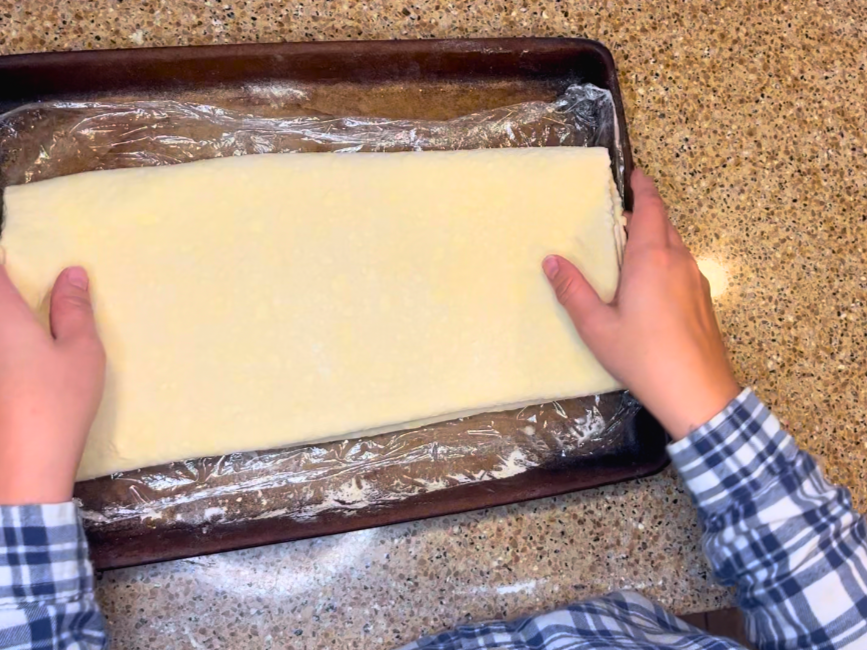 Placing puff pastry dough onto a baking sheet.