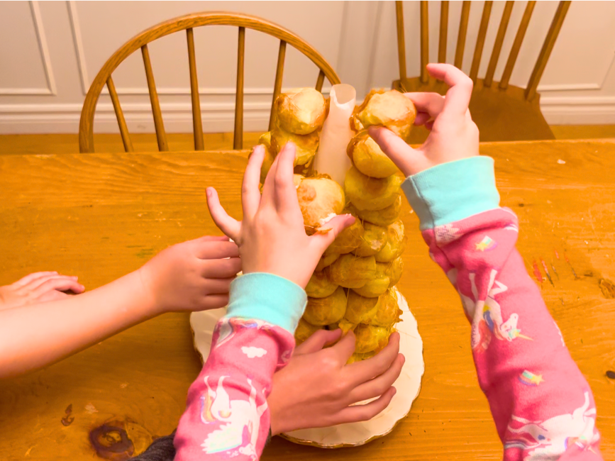 Some children removing profiteroles from a croquembouche.