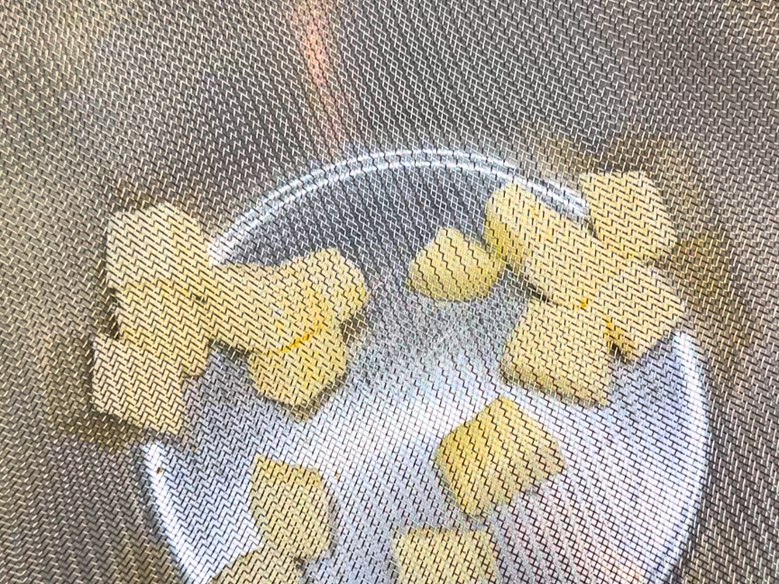 A strainer over top of a metal bowl with cubes of butter in the bottom.