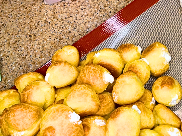 A tray of profiteroles filled with cream.