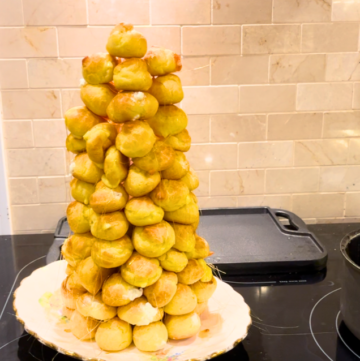 A croquembouche on a white floral plate sitting on a stove top.