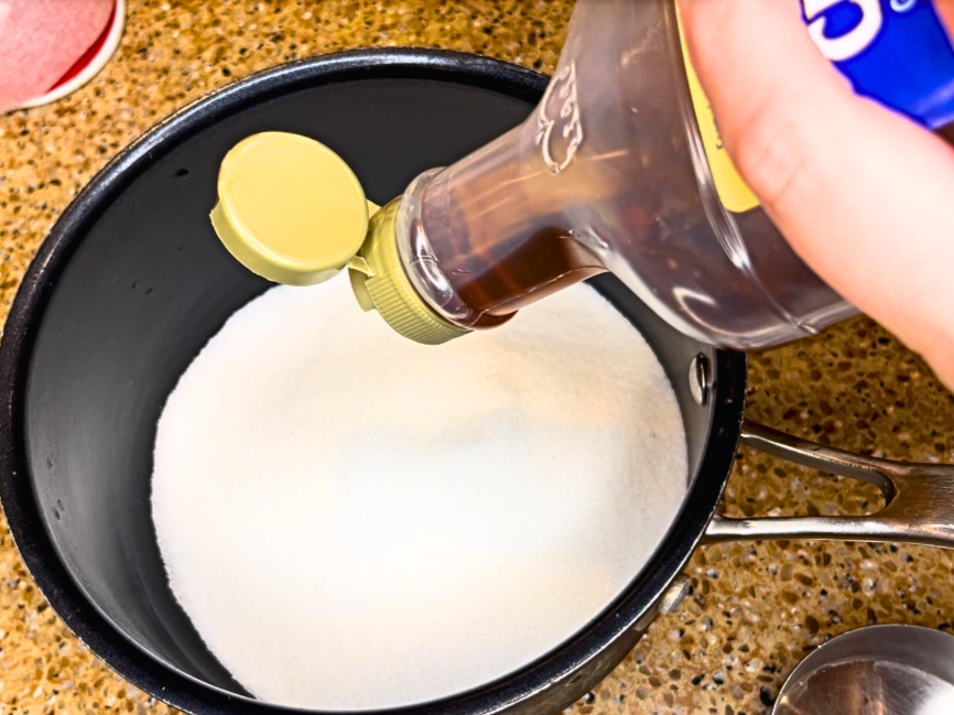 Woman adding corn syrup to a sauce pot with white sugar in it.