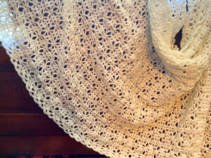 A white crochet blanket draped across a headboard.