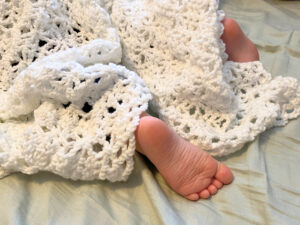 A baby sleeping under a white blanket.