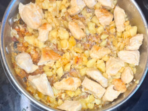 A frying pan with onions and chicken pieces.