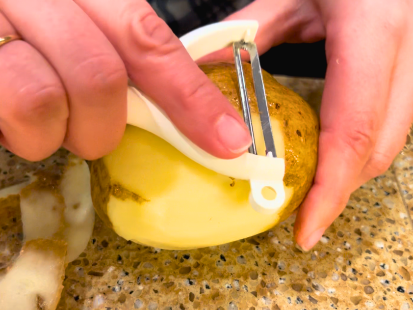 Woman peeling a potato.