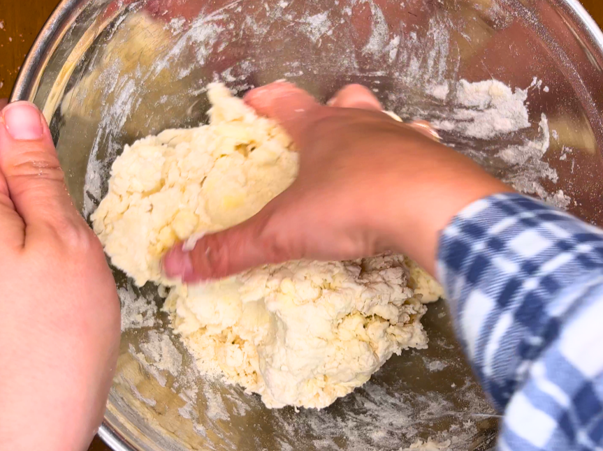 Woman collecting biscuit dough together.