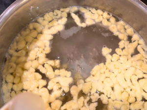 Spaetzle cooking in a pot of boiling water.