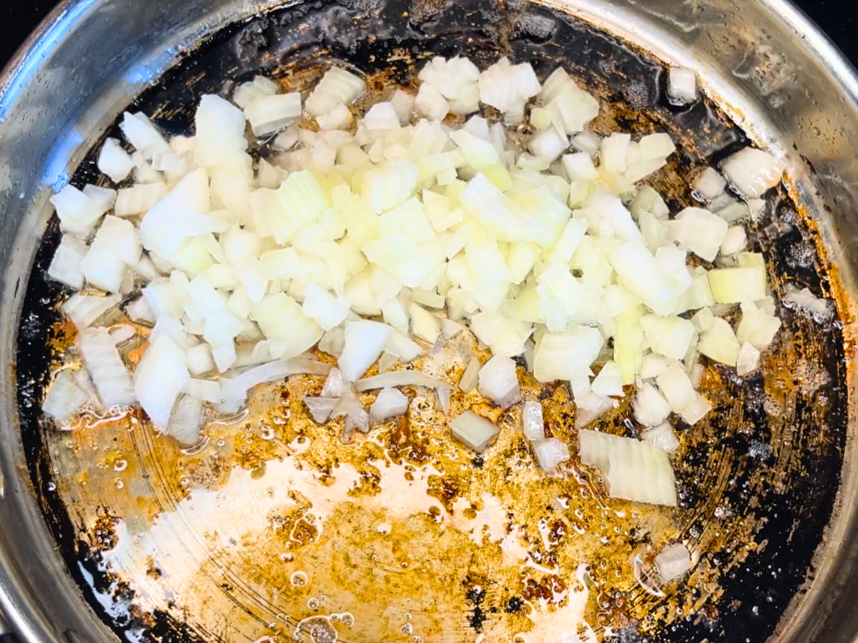 Chopped onions in a metal frying pan with butter melted.