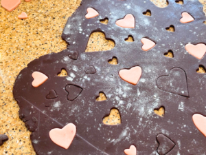 Chocolate sugar cookie dough, with cut out hearts inserted with pink dough.