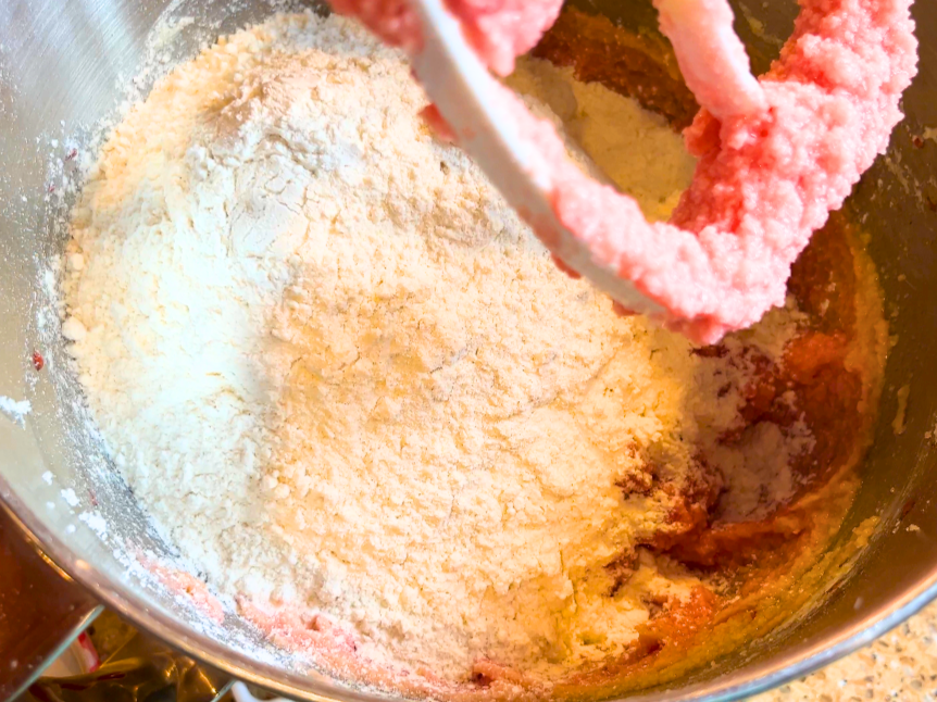 Flour being added to pink strawberry cookie dough.