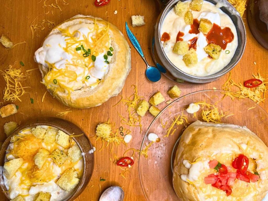 Four bowls of potato soup with different toppings on each