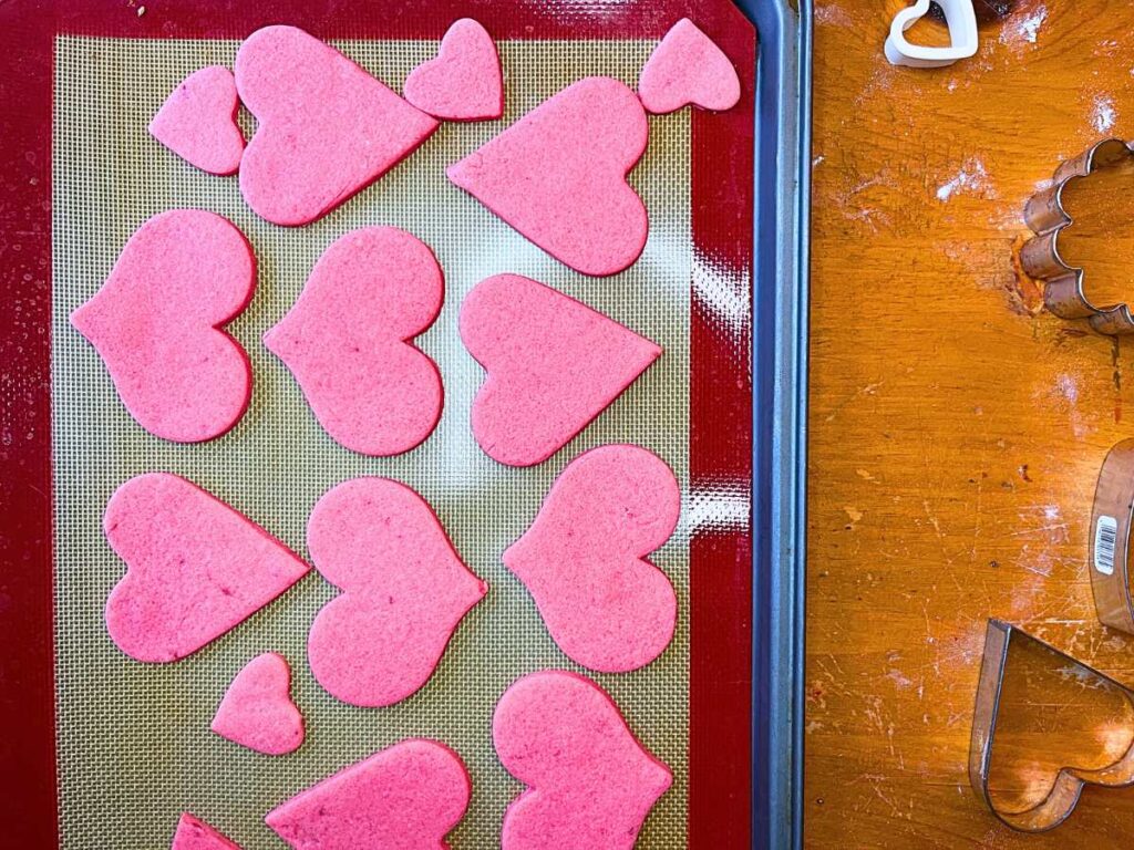 A lined baking sheet with heart cookies on it.