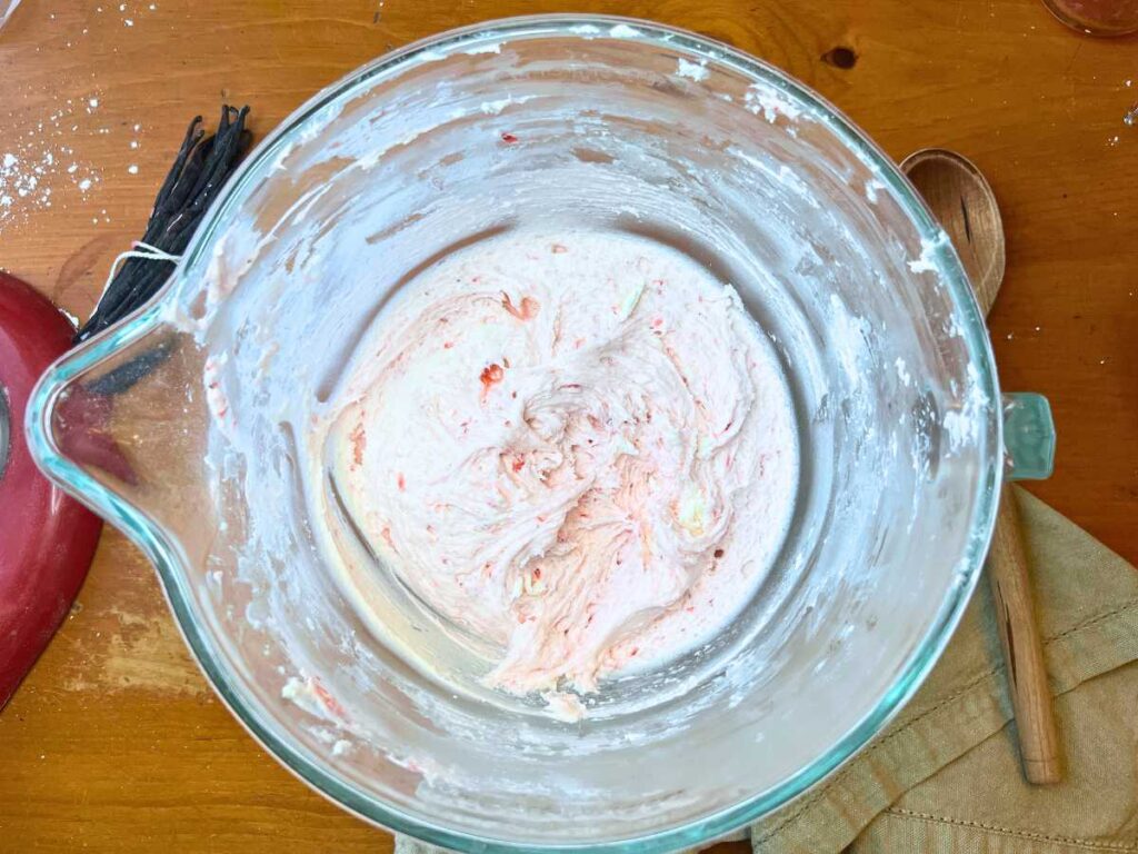 A glass bowl with strawberry icing inside.