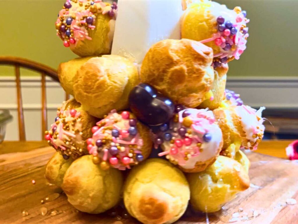 A partially built croquembouche decorated with pink sprinkles and chocolate hearts.