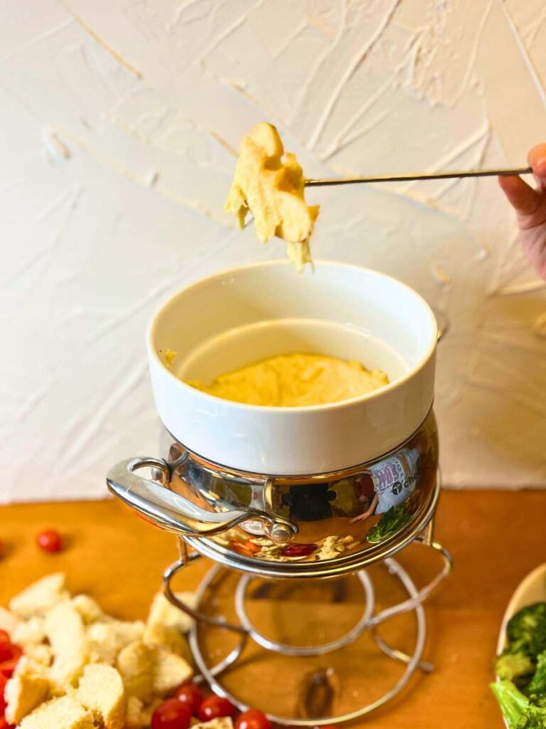 A child is dipping bread into a cheese fondue.