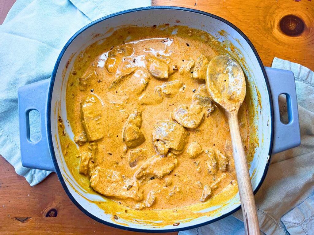 A large Dutch oven with a creamy chicken paprika inside.