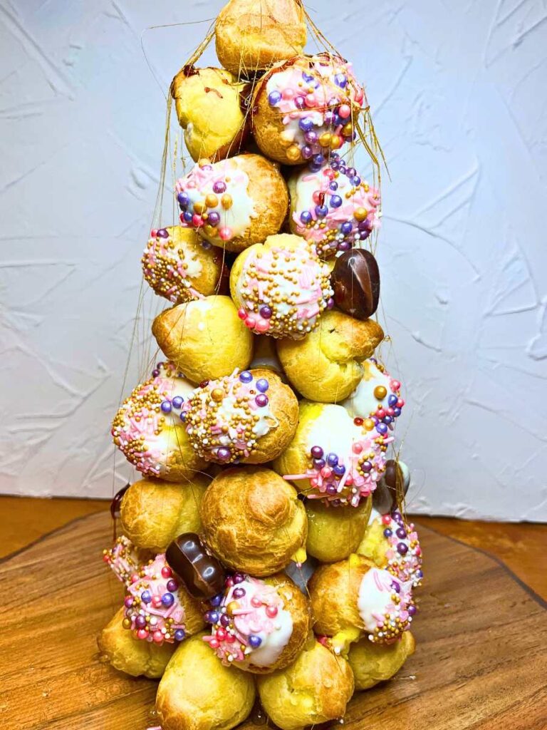 A croquembouche decorated with pink sprinkles and chocolate hearts.