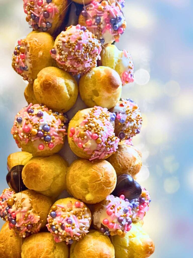 A tower of profiteroles. Some are decorated with sprinkles.