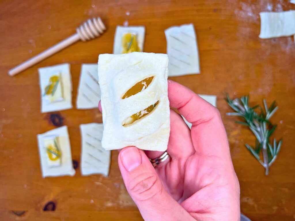 A woman in holding an unbaked Brie and Honey appetizer.