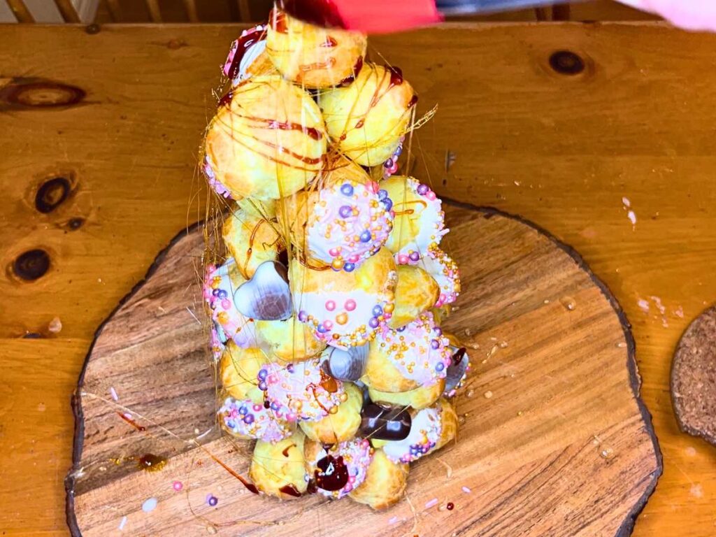 A woman is spinning caramel sugar around a croquembouche.