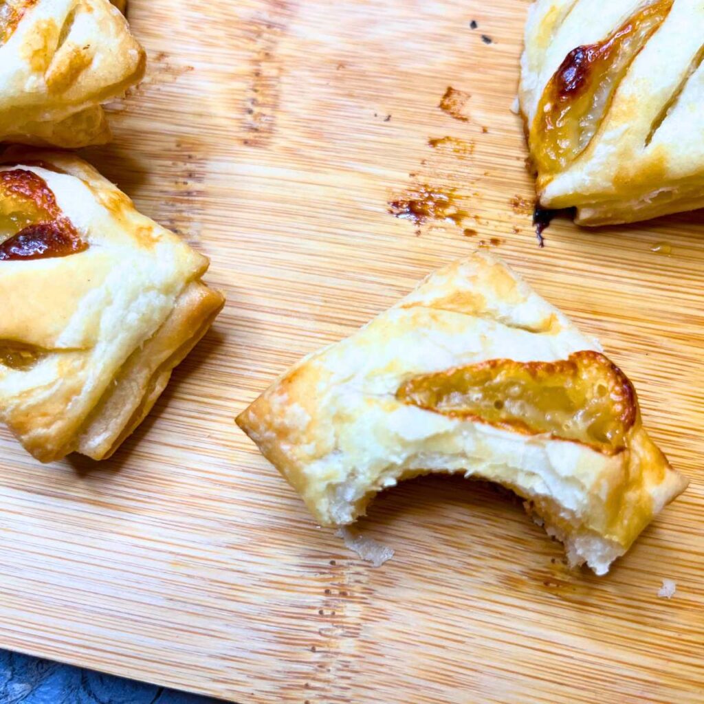 Puff pastry appetizers full of Brie, honey, and rosemary. The one in front has a bite out of it.