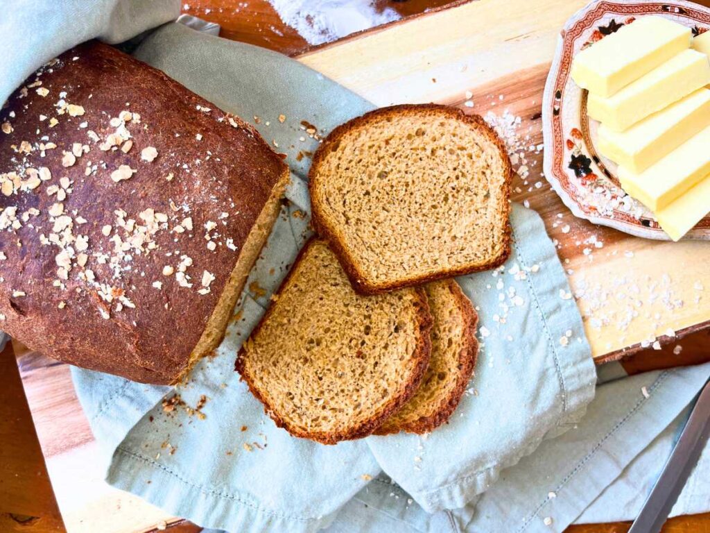 An overhead view of a partially sliced loaf of oatmeal brown bread.