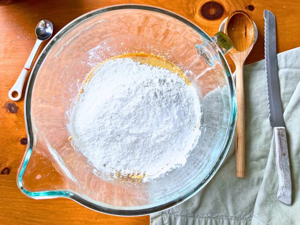 A large glass bowl with a flour mixture inside.