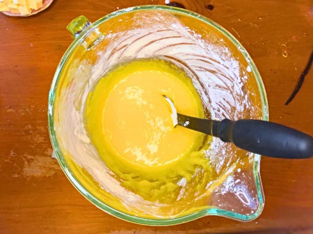 A glass bowl with an egg yolk mixture inside.