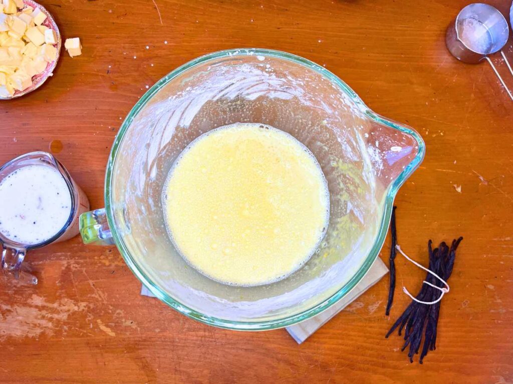 A glass bowl with unthickened pastry cream inside.